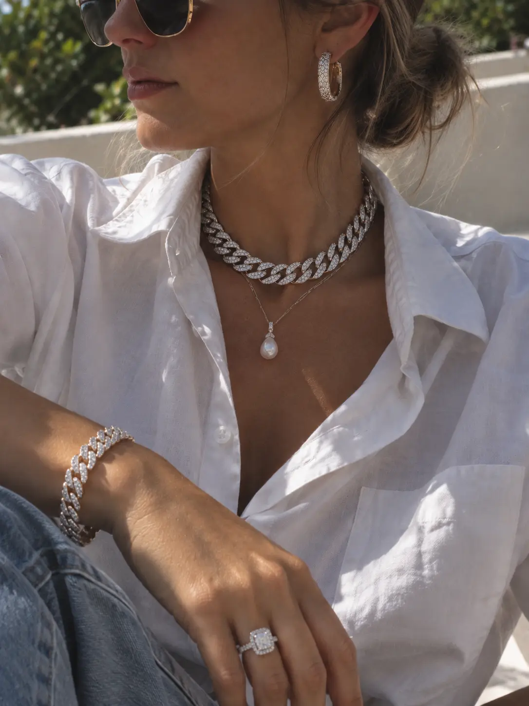 Close-up of a model wearing an iced diamond cuban choker necklace and matching bracelet with an open white shirt.